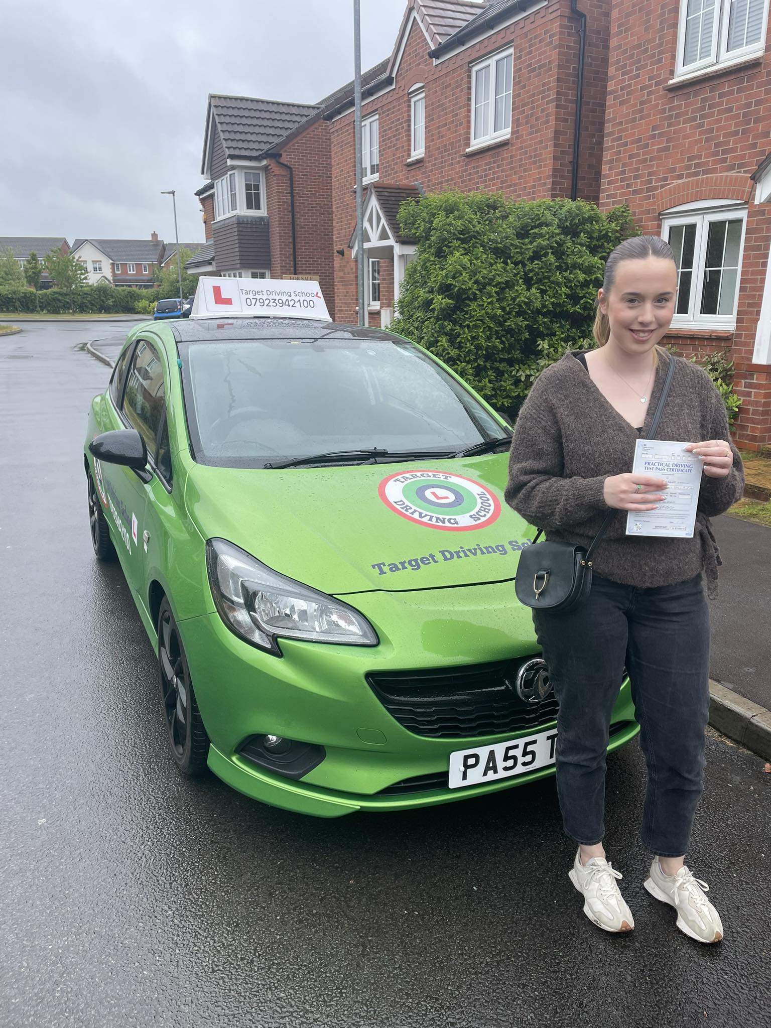 Female student showing driving test pass certificate next to Target Driving School car Telford